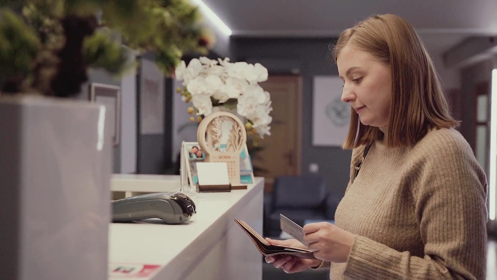 A receptionist taking a card payment at a dental practice front desk
