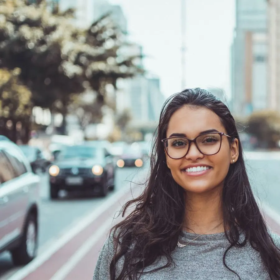Profesional sonriente con gafas en una calle de la ciudad